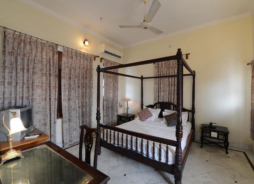 Hotel Harasar Haveli in Bikaner: four-poster bed in a bright guest room with tiled floor and curtains