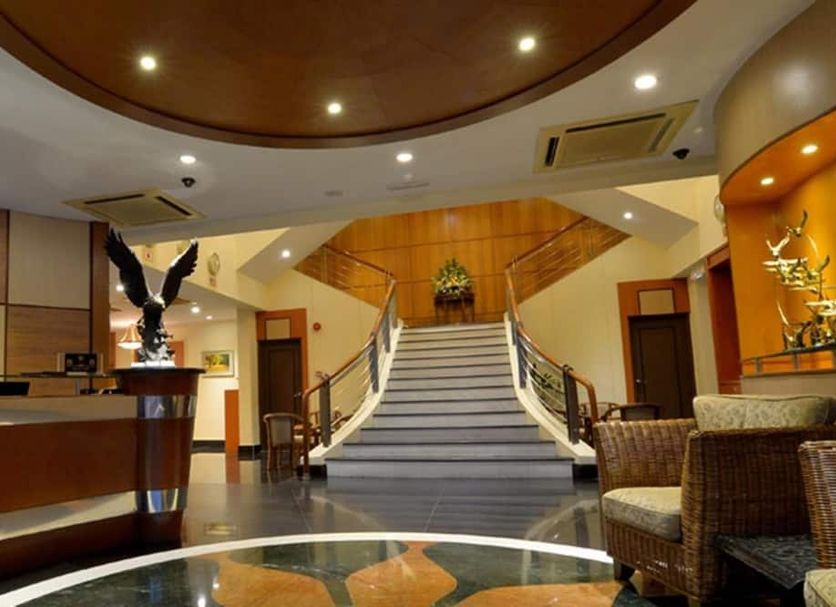 Asiana Hotel Kota Kinabalu lobby with central staircase, reception desk, and wicker seating