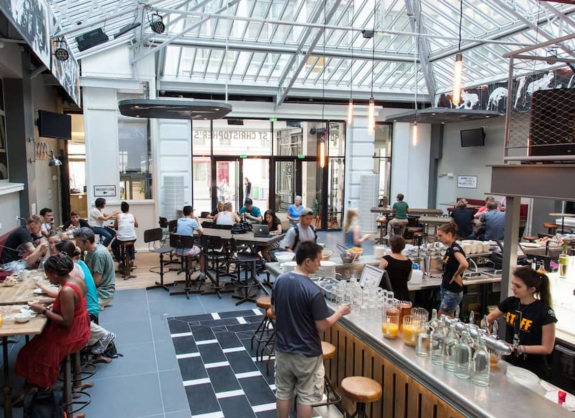 St Christopher's Inn Paris - Gare du Nord bar and dining area in Paris with guests seated under a glass roof