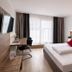Hotel Asgard in Gersthofen guest room with double bed, desk, wall-mounted TV and window seating