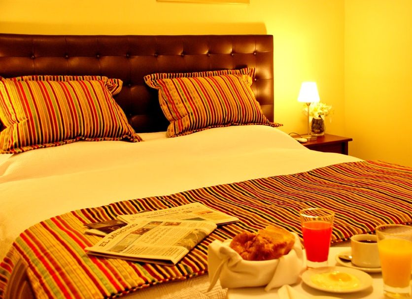 Oporto Hotel Boutique in Santiago guest room with striped bed linens, bedside lamp, and breakfast tray