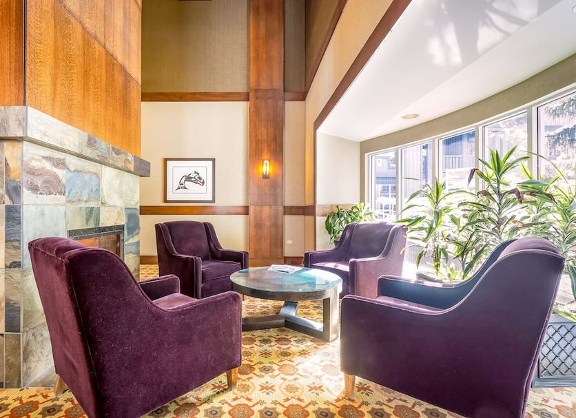 Glacier Lodge in Whistler lounge with purple armchairs, stone fireplace and large windows