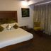 Hotel Airport Centre Point Nagpur room with king bed, armchair, small table and curtained window