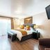 Sunward Park Guest House & Conference Centre room in Boksburg with king bed, bench, TV, and balcony doors