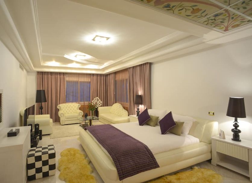 The Penthouse Suites Hotel Tunis guest room with king bed, seating area, and purple accents