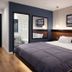 Hotel Mirage Brooklyn guest room with king bed, wall mirror, and framed Brooklyn bridge artwork