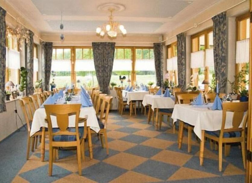 Haus Waldesruh in Kastellaun dining room with set tables, wooden chairs, and large windows