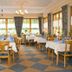 Haus Waldesruh in Kastellaun dining room with set tables, wooden chairs, and large windows