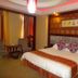 Jinluowan Hotel Ji'an guest room with king bed, sitting chairs, and warm red lighting