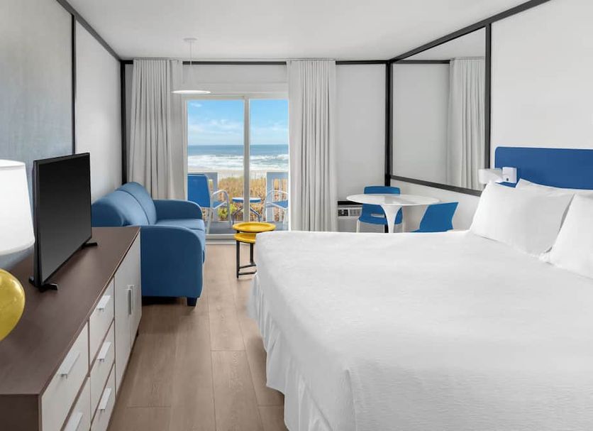 Montauk Blue Hotel room with king bed, blue chair, TV, and balcony view of the beach in Montauk