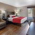 SureStay by Best Western Greenville guest room with king bed, armchair, desk, lamp and sliding door to outside.