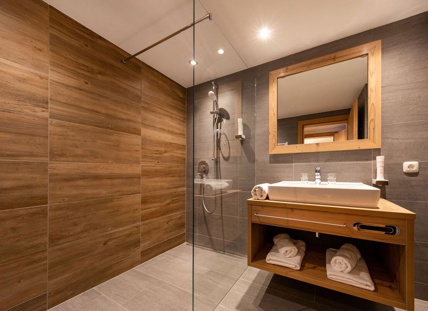 Das Grünholz Aparthotel bathroom in Mühlbach am Hochkönig with wood-paneled walls and walk-in shower