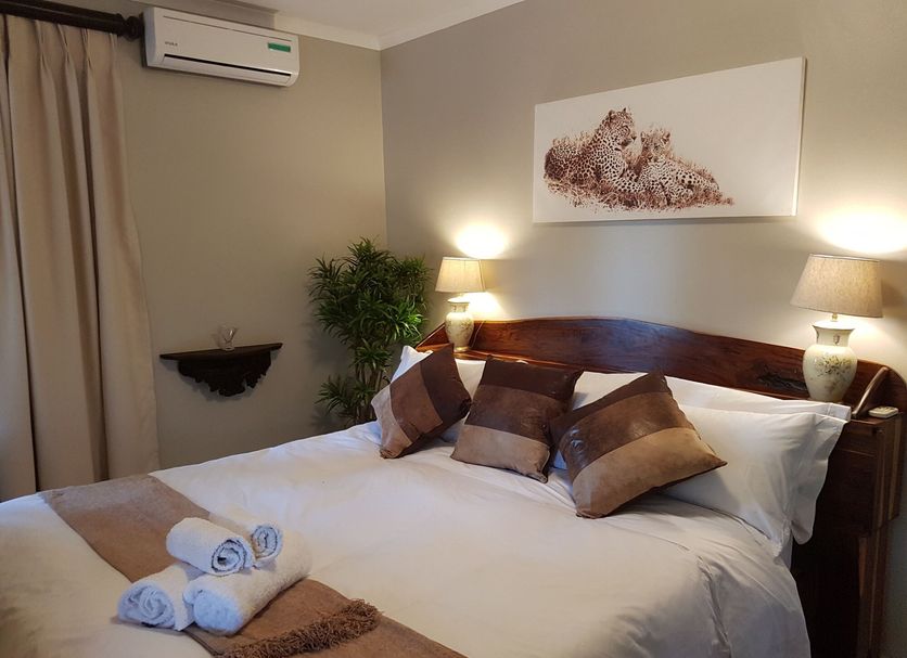 Benka Lifestyle Country Cottages in Lobamba bedroom with king bed, bedside lamps and wall art