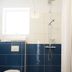 Media Luna Guesthouse in Seydisfjordur bathroom with shower, toilet, blue tile walls, and dark floor.