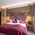 Hotel Jägerhof Mayrhofen bedroom with floral headboard, burgundy bedspread and wood-paneled walls