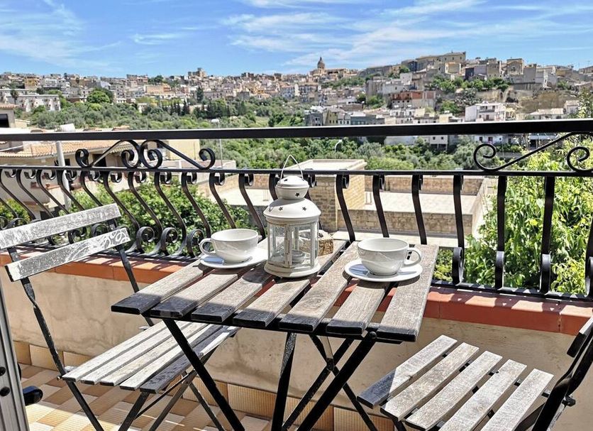 Villa Ambra B&B in Noto balcony with table, chairs and city view over historic rooftops