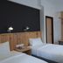 De House Hotel in Sibu room with two single beds, wood headboard, desk, mirror and bench