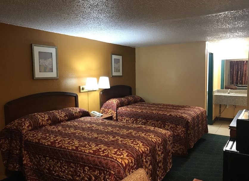 Travel Inn Weatherford guest room with two double beds and a vanity area