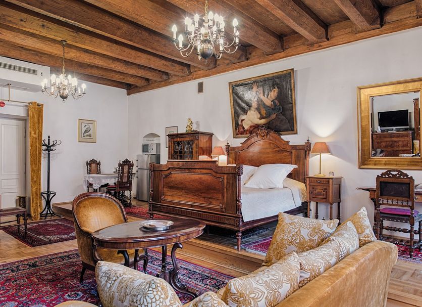 Orlowska Townhouse Apartments, Krakow: ornate bedroom with carved wooden bed, chandelier, rugs and sofa