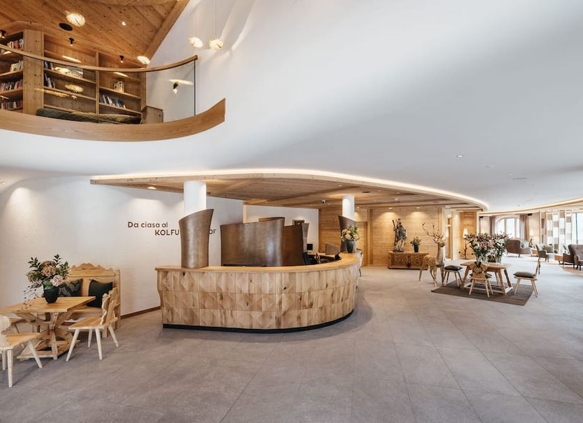 Kolfuschgerhof Mountain Resort in Corvara in Badia lobby with curved wood reception and seating area