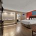Quality Inn Wayne - Fairfield Area guest room with king bed, red accent wall, and open bathroom area in Wayne
