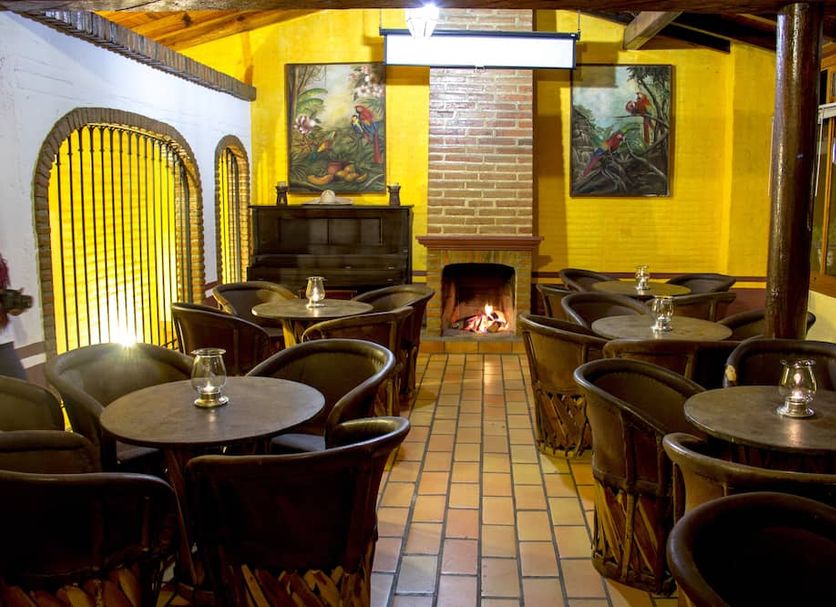 Huerta Real Mazamitla in Mazamitla, cozy rustic lounge with fireplace and round dining tables