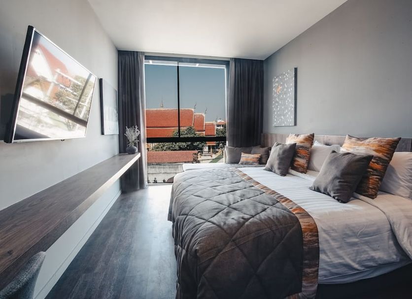 Spice House Chiang Mai guest room with king bed, wall-mounted TV, and balcony city view