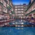 Hotel Neo + Kuta Legian in Kuta with a central outdoor pool and lounge seating at dusk
