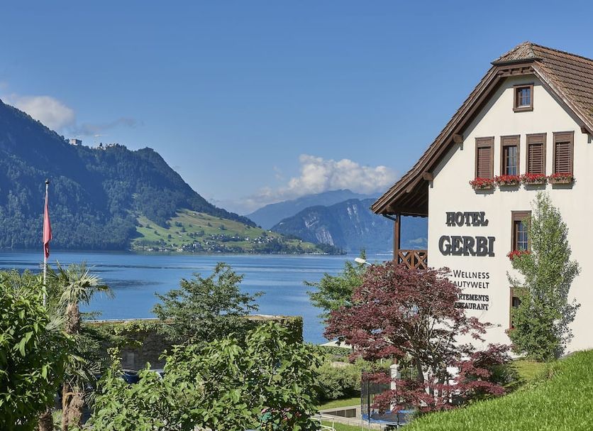 Lake and mountain view from Hotel Alexander in Weggis, with garden and traditional chalet-style building