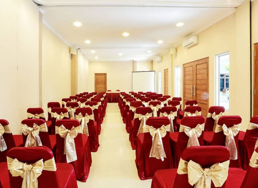 Syariah Arini Hotel in Surakarta City: rows of red banquet chairs with gold bows in a bright event room