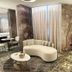 Iris Hotel Erbusco lounge with curved beige sofa, round tables, patterned carpet and mural walls