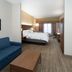Holiday Inn Express & Suites Talladega guest room with blue sofa, bed and desk in Talladega