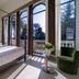 Hotel Villa Soligo guest room with four-poster bed, green chair, and balcony views in Farra di Soligo