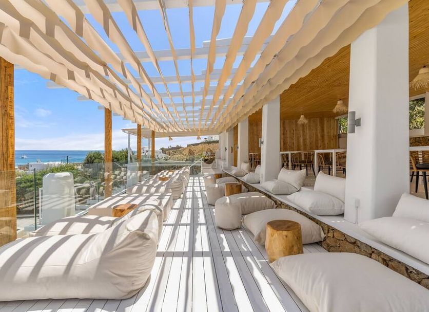 Penelope Village in Kalafati: shaded poolside lounge with daybeds, glass railing, and sea view