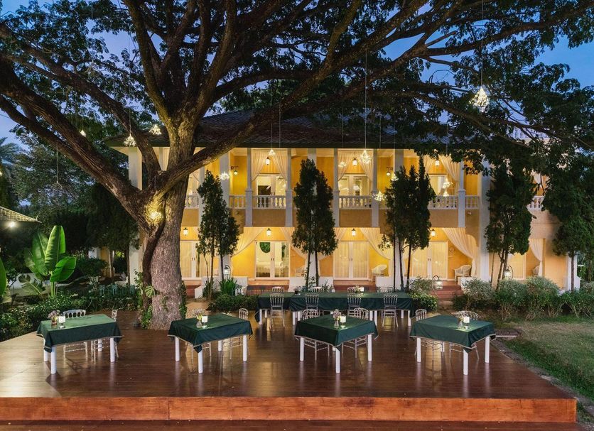 Rosario Oasis Resort in Chiang Mai with a lit outdoor dining deck beneath a large tree