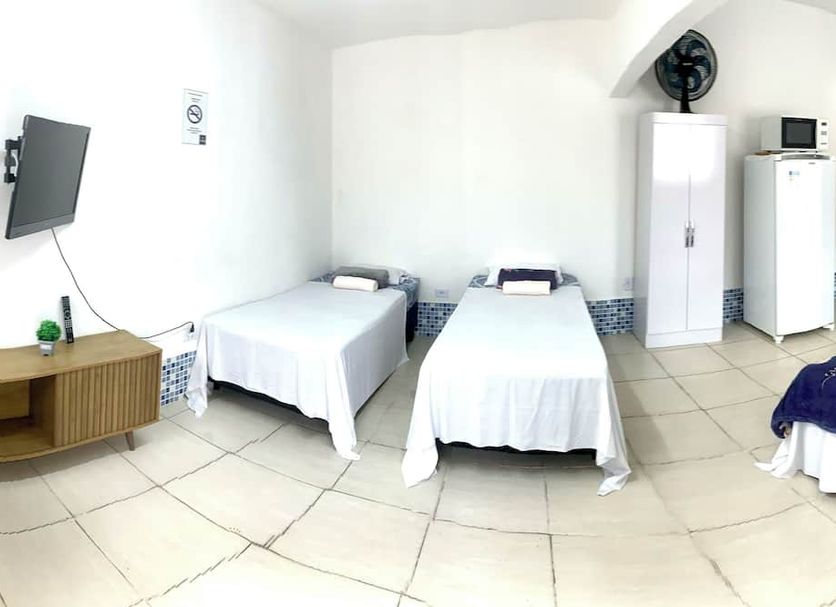 Pousada Aconchego Ocian in Praia Grande: simple guest room with twin beds, TV, wardrobe and mini fridge.