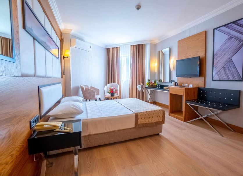 Aydinbey Gold Dreams Alanya guest room with double bed, TV, desk and balcony curtains