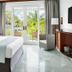 Couples Negril guest room with king bed, balcony doors, and tropical garden view in Negril