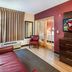 Red Roof Plus Long Island - Garden City room in Westbury with sofa, TV, chair and glass doors