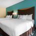 AmericInn by Wyndham St. Cloud MN Shopping Area guest room with two beds and teal accent wall