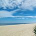 Beachfront view at Hostel Dos Gringos in Maricá with sandy shore, ocean, and blue sky