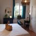 Les Lauriers Saint-Tropez guest room with bed, desk, window, teal curtains and woven pendant light