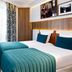 Hotel Eiffel Turenne in Paris guest room with twin beds, teal bedding, and geometric curtains