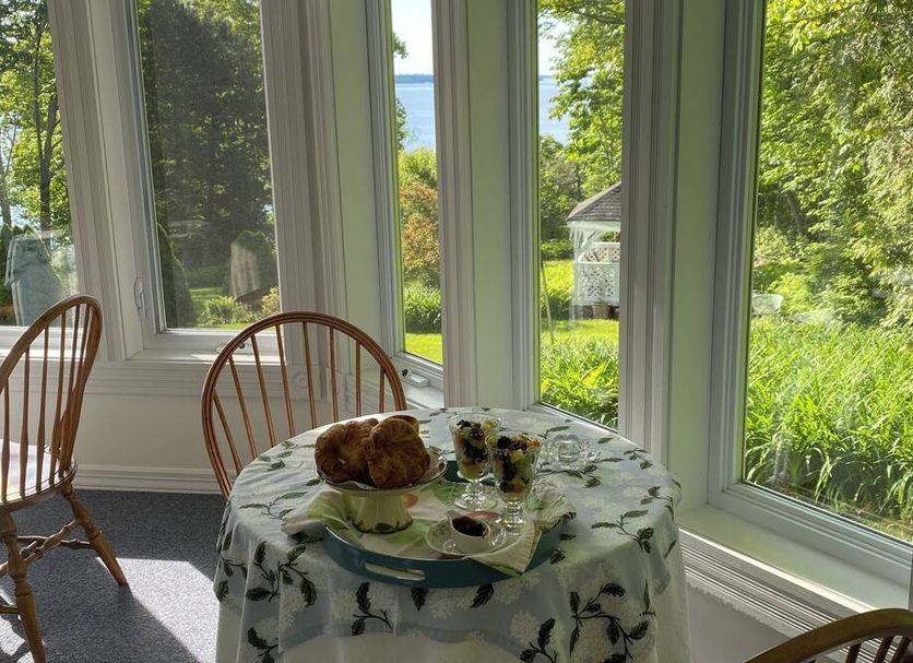 Victorian by the Sea in Lincolnville: breakfast table by large windows with sea and garden views