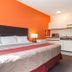 Motel 6 Surrey Bc room with king bed, orange accent wall, kitchenette and TV in Surrey