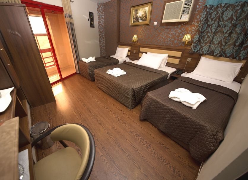Downtown Hotel Dubai room with three single beds, wood floor, and air conditioner