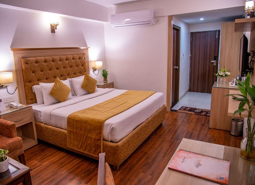 Sun Park Resort, Chandigarh bedroom with king bed, wooden floor, bedside lamps and seating area