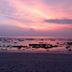 Relax Beach House in Ko Lanta with a pink sunset over a rocky beach and calm sea