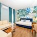 Le Palazzine Hotel Vlorë room with sofa bed, desk, teal curtains and tropical mural