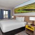 Days Inn by Wyndham Mason City guest room with queen bed, desk, TV, window, and landscape wall art